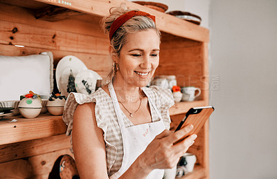 Buy stock photo Woman, happy and phone in workshop for pottery blog, social media and check website inventory. Sculpture artist, ceramic designer and mobile for online sales, ecommerce stats and selling art product