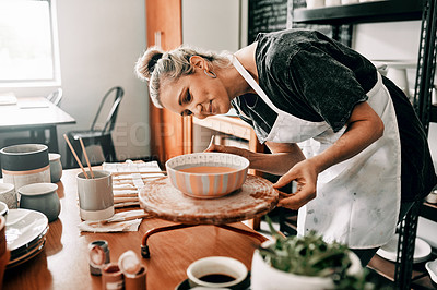 Buy stock photo Cropped shot of an attractive mature woman standing alone and painting a pottery bowl in her workshop