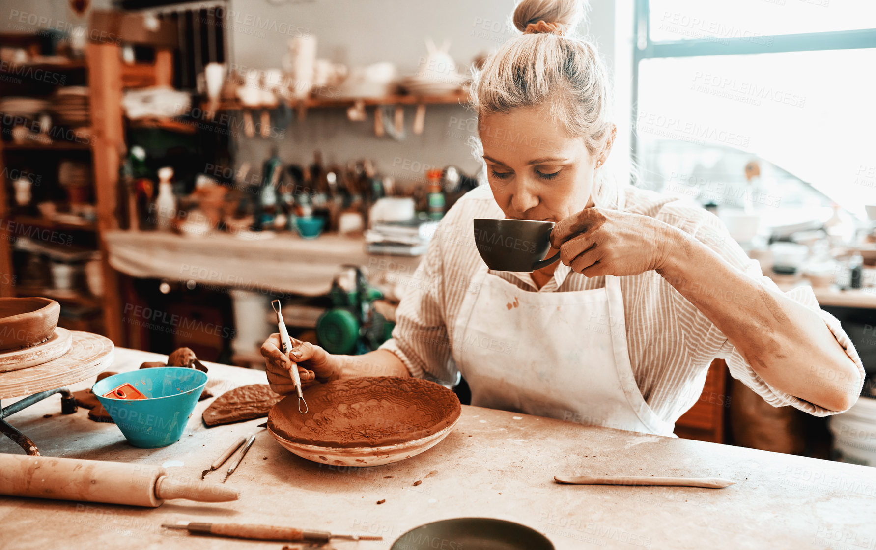 Buy stock photo Drinking coffee, pottery and creative woman in workshop for carving pattern or design with ribbon tools. Artist, equipment and person sculpting ceramic for art, shape and decoration for manufacturing