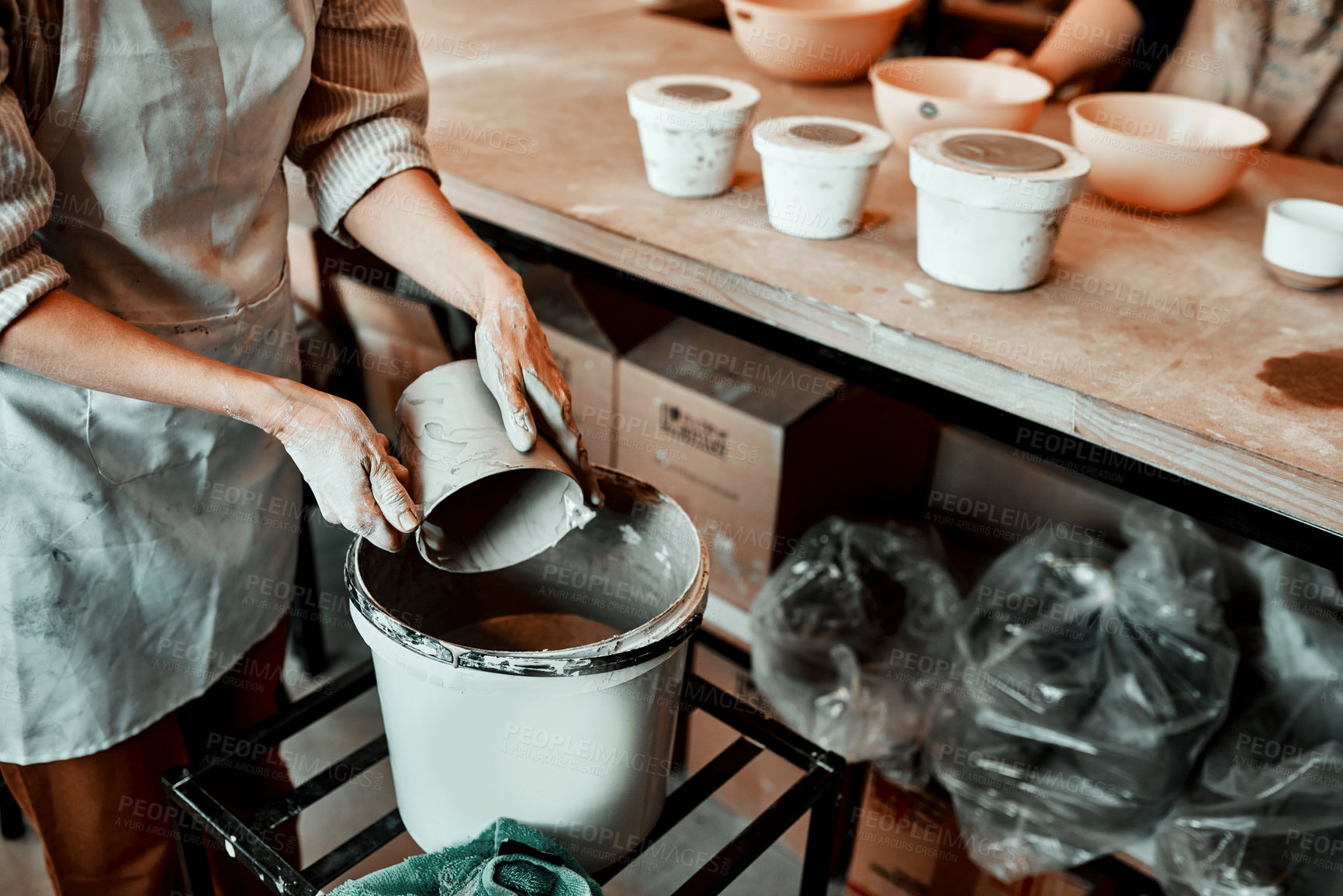 Buy stock photo Person, glaze and pottery bucket in studio for ceramic, shape and craft with easy application. Artist, bowl and cleaning or mixing slip as potter in workplace for creative art, process and handmade