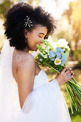 Buy stock photo Shot of a happy and beautiful young bride smelling her bouquet of flowers outdoors on her wedding day