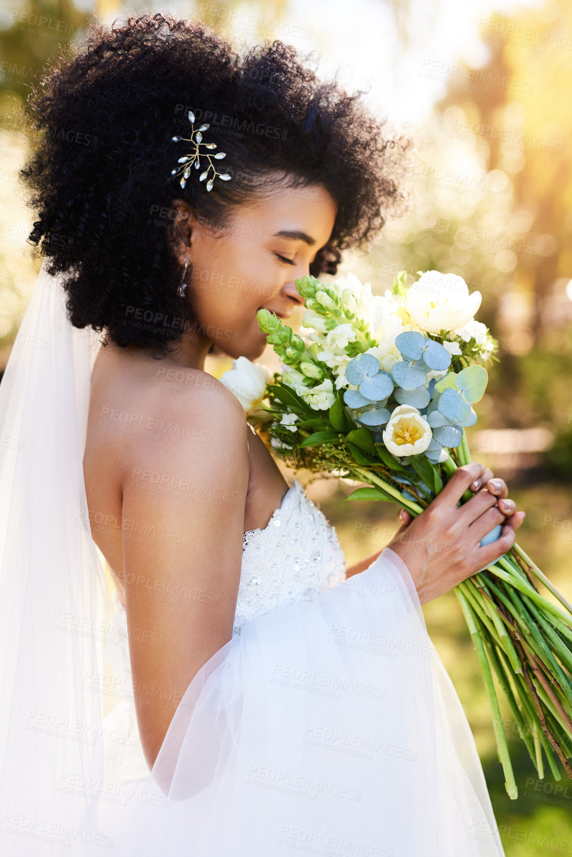 Buy stock photo Shot of a happy and beautiful young bride smelling her bouquet of flowers outdoors on her wedding day