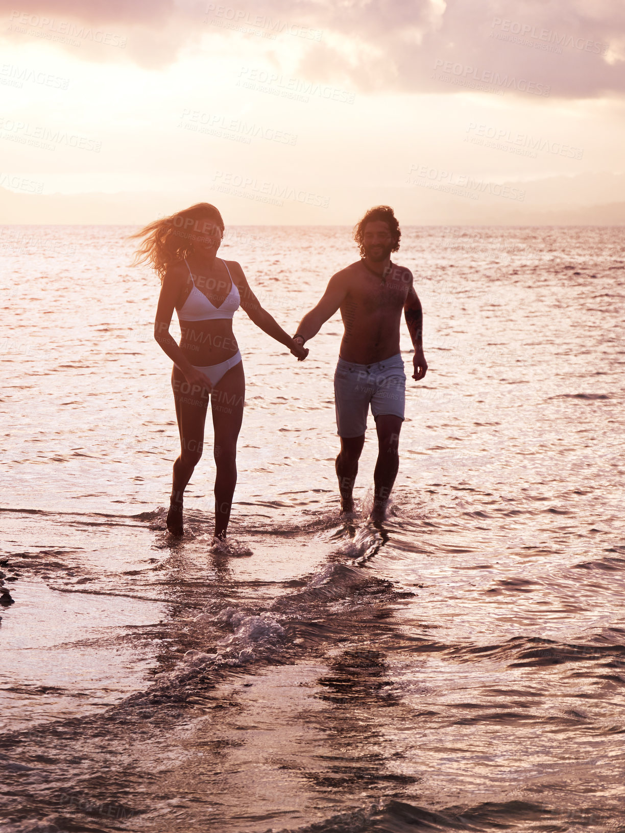 Buy stock photo Shot of a young couple running along the beach