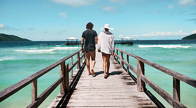 Buy stock photo Travel, freedom and rear view of couple at beach walking, holding hands and relax on ocean jetty with blue sky background. Summer, holiday and behind man with woman at sea, traveling or Bali romance
