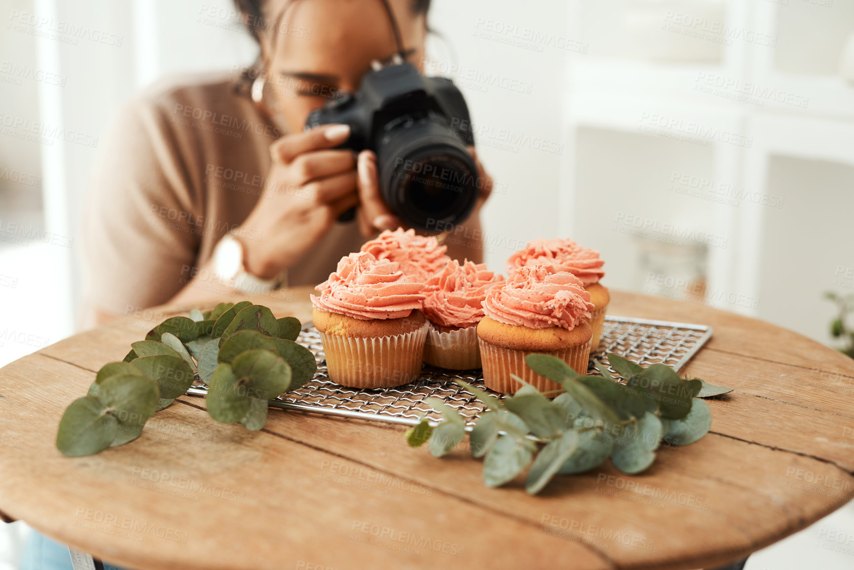Buy stock photo Cropped shot of an attractive young businesswoman using her camera to photograph cupcakes for her blog