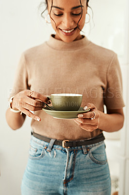 Buy stock photo Cropped shot of an attractive young woman standing alone in her home and holding a cup of coffee