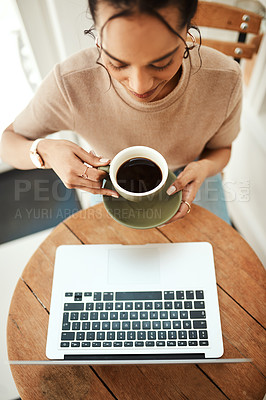 Buy stock photo High angle shot of an attractive young businesswoman sitting and enjoying a cup of coffee while using her laptop