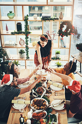 Buy stock photo High angle shot of a group of cheerful young friends making a toast while dining together at Christmas