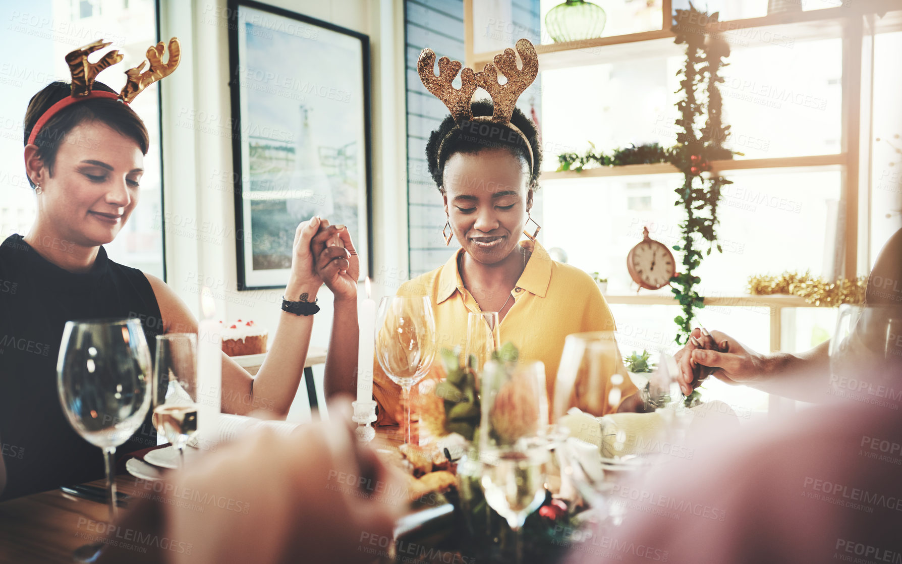 Buy stock photo Cropped shot of a group of young friends saying grace while dining together at Christmas