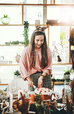 Buy stock photo Cropped shot of an attractive young woman cutting the cake during Christmas lunch with her friends at home