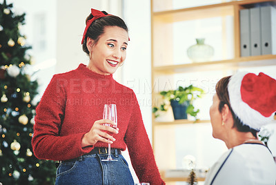 Buy stock photo Shot of two attractive young women drinking champagne and celebrating together at their office Christmas party