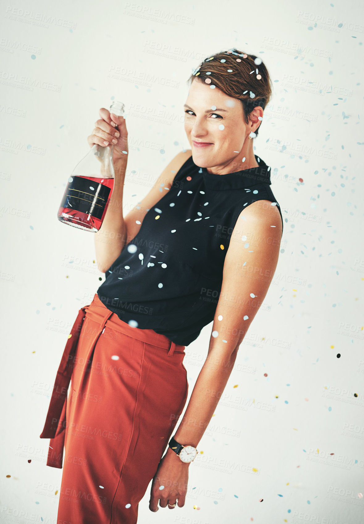 Buy stock photo Shot of an attractive young woman drinking a bottle of champagne and celebrating against a grey background