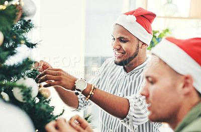 Buy stock photo Shot of two young businessmen decorating a Christmas tree in their office at work