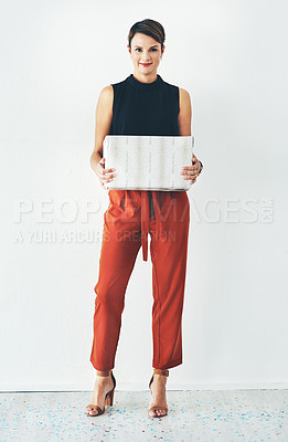 Buy stock photo Full length shot of an attractive young woman holding a wrapped present against a grey background