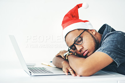 Buy stock photo Cropped shot of a handsome young businessman sleeping on his desk while working in his office on Christmas Eve
