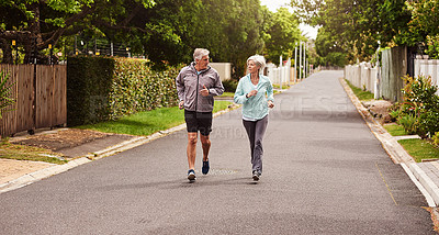 Buy stock photo Shot of a cheerful senior couple having a jog together outside in a suburb