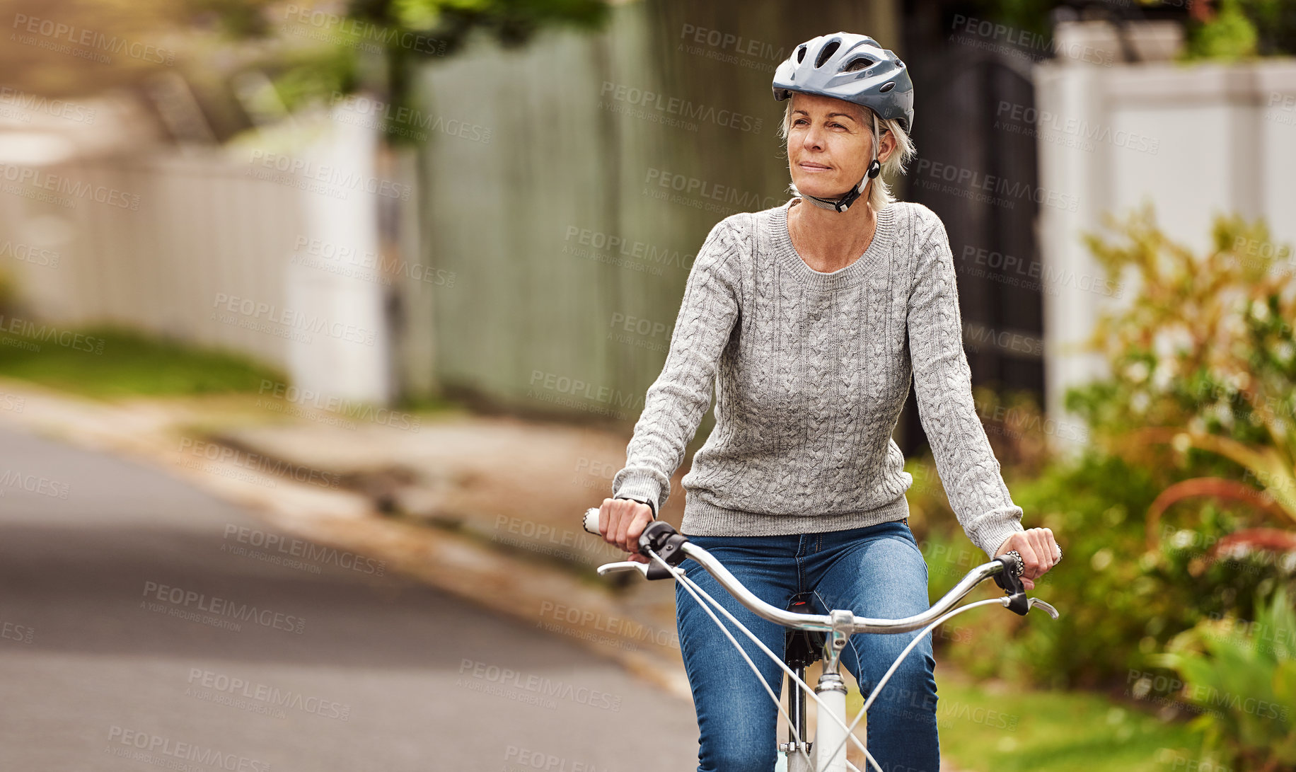 Buy stock photo Cropped shot of a cheerful senior woman riding on a bicycle by herself outside in a suburb