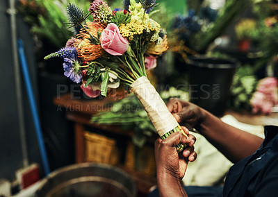Buy stock photo Cropped shot of an unrecognizable florist wrapping up a bouquet of flowers inside a plant nursery