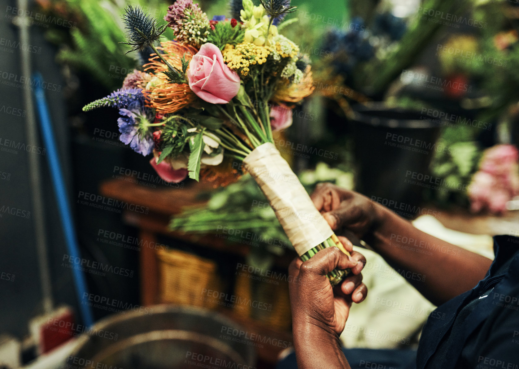 Buy stock photo Cropped shot of an unrecognizable florist wrapping up a bouquet of flowers inside a plant nursery