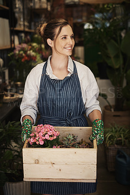 Buy stock photo Cropped shot of an attractive young florist holding a crate full of flowers inside her plant nursery