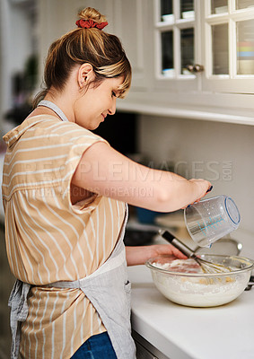 Buy stock photo Cropped shot of an unrecognizable woman adding milk to her cake mixture