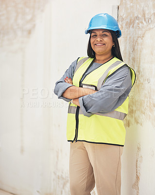 Buy stock photo Cropped portrait of an attractive young female construction worker standing with her arms folded on site