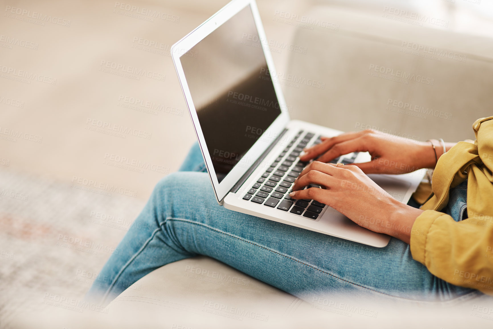 Buy stock photo Cropped shot of an unrecognizable businesswoman sitting on her couch and blogging from her laptop while at home