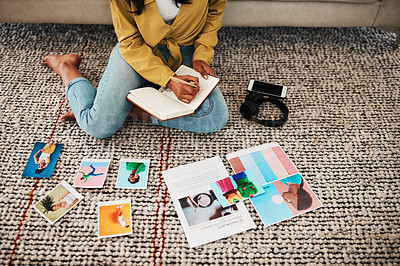 Buy stock photo Cropped shot of an unrecognizable businesswoman sitting on her living room floor and going through polaroids while making notes