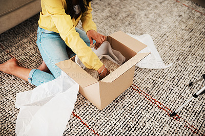 Buy stock photo Cropped shot of an unrecognizable businesswoman sitting alone on her living room floor and opening up a mystery box