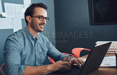 Buy stock photo Cropped shot of a handsome young male architect smiling while working on a laptop in his office