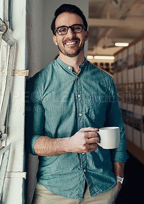 Buy stock photo Cropped portrait of a handsome young businessman smiling while holding a cup of coffee in an office
