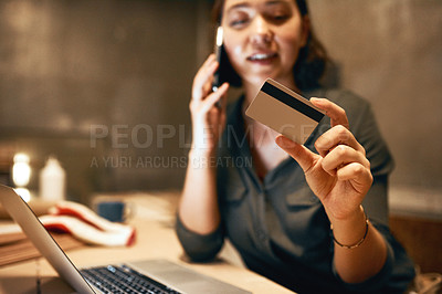Buy stock photo Cropped shot of an attractive young female carpenter holding her credit card and doing online shopping while talking on her cellphone inside of a workshop