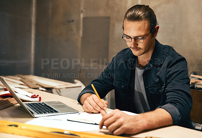 Buy stock photo Cropped shot of a focused young male carpenter working on a project inside of a workshop at night