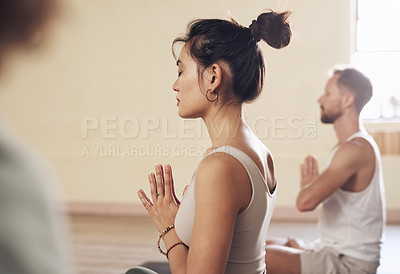 Buy stock photo Shot of a group of young people meditating and practicing yoga together inside a yoga studio