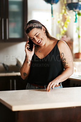 Buy stock photo Shot of a young woman using a smartphone in the kitchen at home