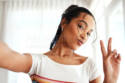 Buy stock photo Cropped portrait of an attractive young blogger standing in her home and making a peace sign gesture for a selfie