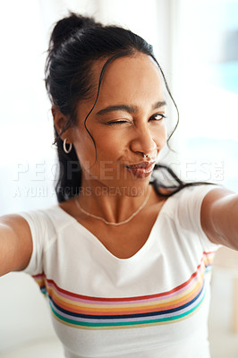 Buy stock photo Cropped portrait of an attractive young blogger pouting and winking for a selfie while standing in her home