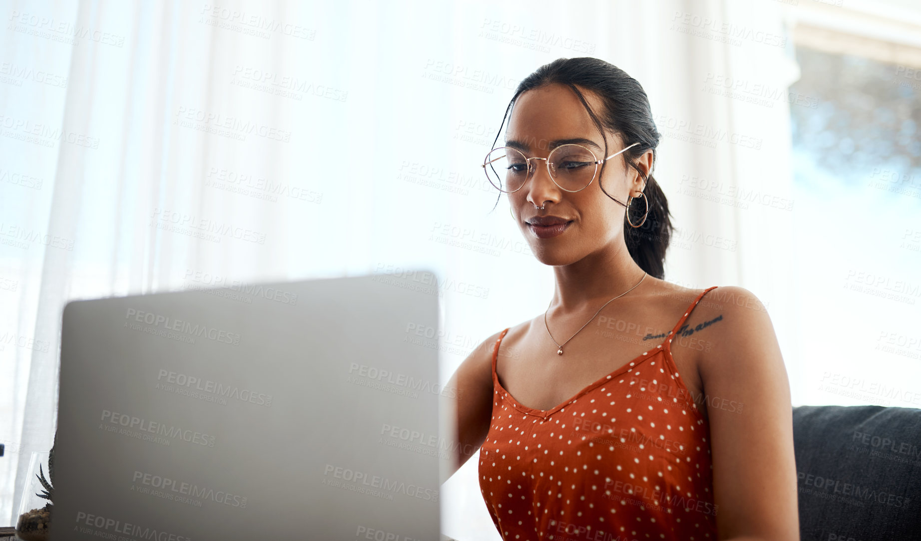 Buy stock photo Cropped shot of an attractive young businesswoman sitting in her home office and using her laptop