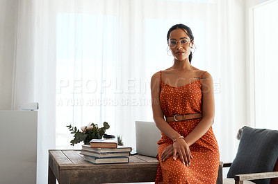 Buy stock photo Cropped portrait of an attractive young businesswoman sitting on her desk in her home office during a day off