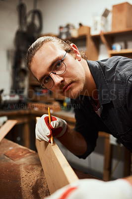 Buy stock photo Portrait of a focused young carpenter doing measurements on a piece of wood inside of a workshop at night