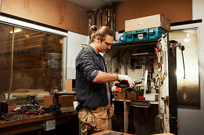 Buy stock photo Cropped shot of a focused young male carpenter opening a toolbox to use while working inside of a workshop at night