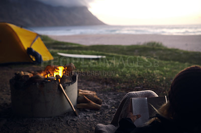 Buy stock photo Cropped shot of a young woman reading a book while out camping