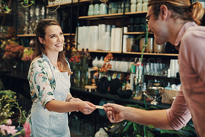 Buy stock photo Cropped shot of an attractive young businesswoman standing in her floristry and accepting a customer's credit card for a payment