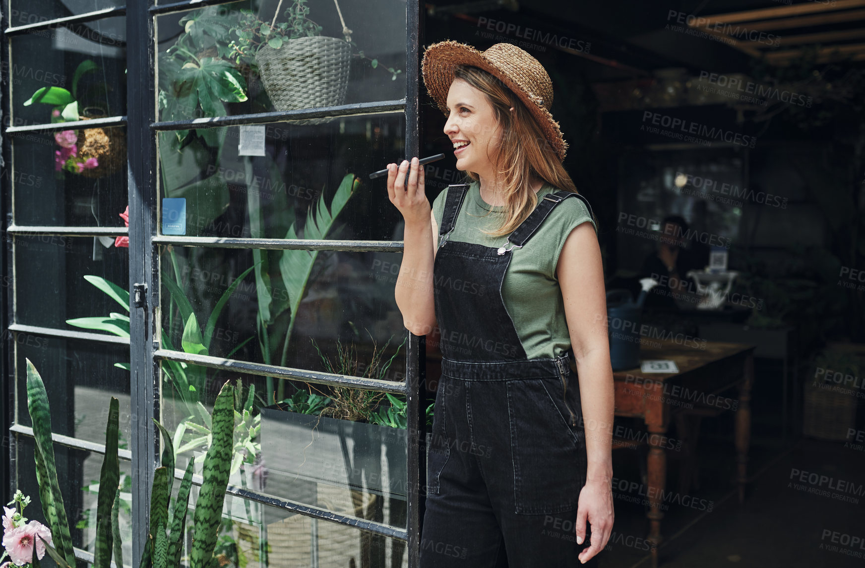 Buy stock photo Woman, florist and happy at door with smartphone for voice note recording, communication and networking. Small business, female person and smile or satisfied with conversation for flower order