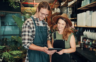 Buy stock photo Cropped shot of two young business owners standing in their floristry together and using a tablet