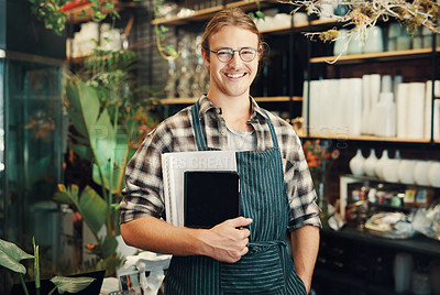 Buy stock photo Cropped portrait of a handsome young business owner standing in his floristry alone and holding paperwork and a tablet