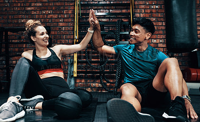 Buy stock photo Cropped shot of two cheerful young sportspeople high fiving each other while taking a break in a gym