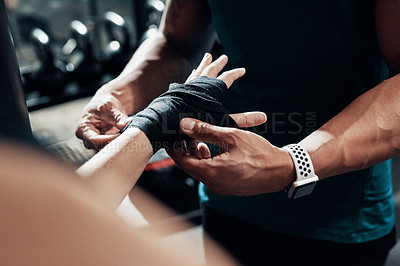 Buy stock photo Cropped shot of an unrecognizable sportswoman getting her hand wrapped by her personal trainer in a gym