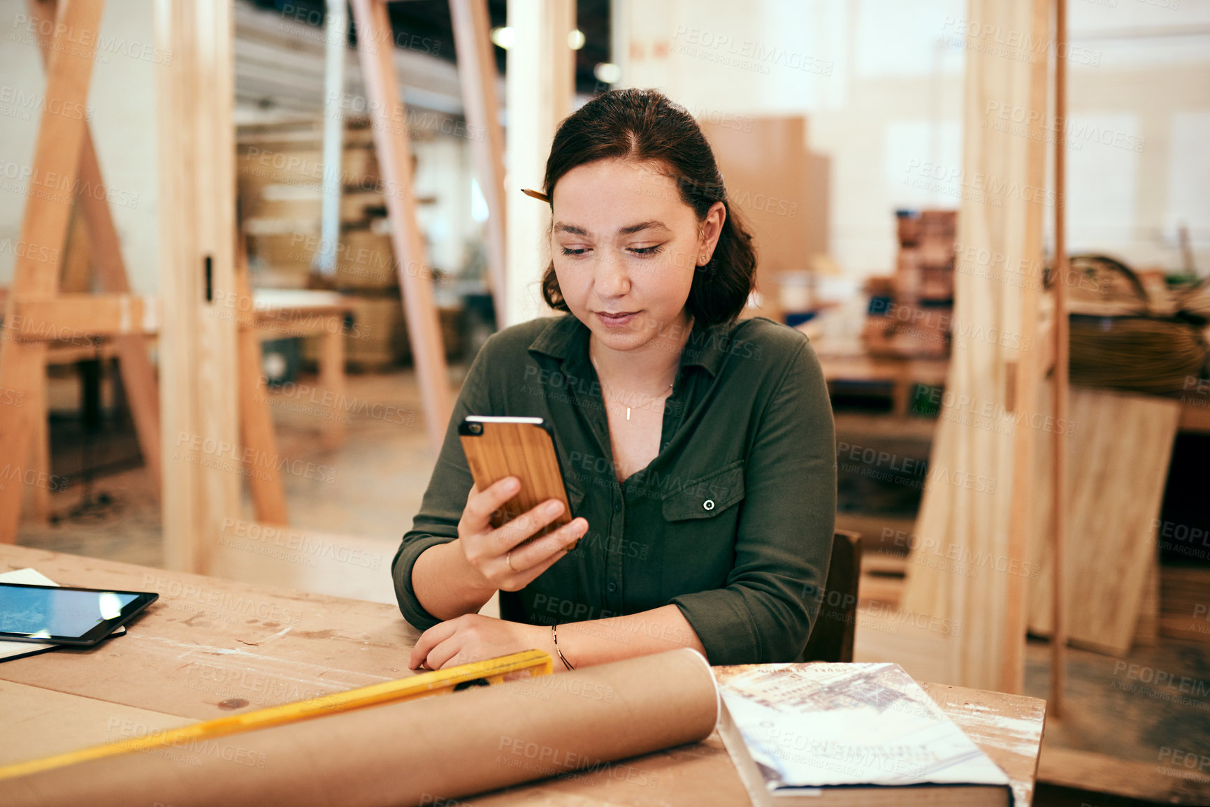Buy stock photo Cropped shot of a female carpenter using her cellphone while sitting in her workshop