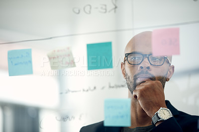 Buy stock photo Cropped shot of a young businessman brainstorming with notes on a glass wall in an office